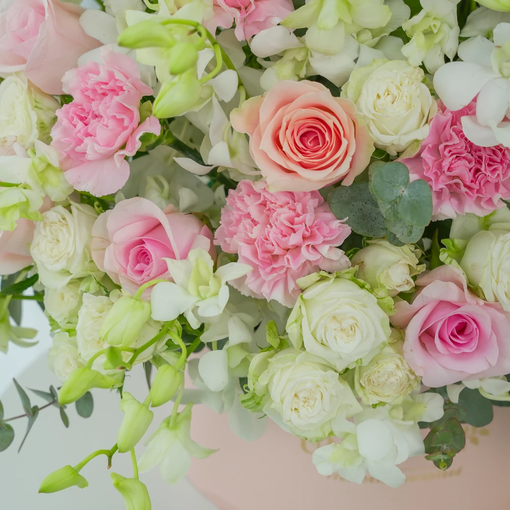 A box arrangement of 20 white orchids, 12 pink roses, 12 pink carnations and 5 white spray roses with green fillers.