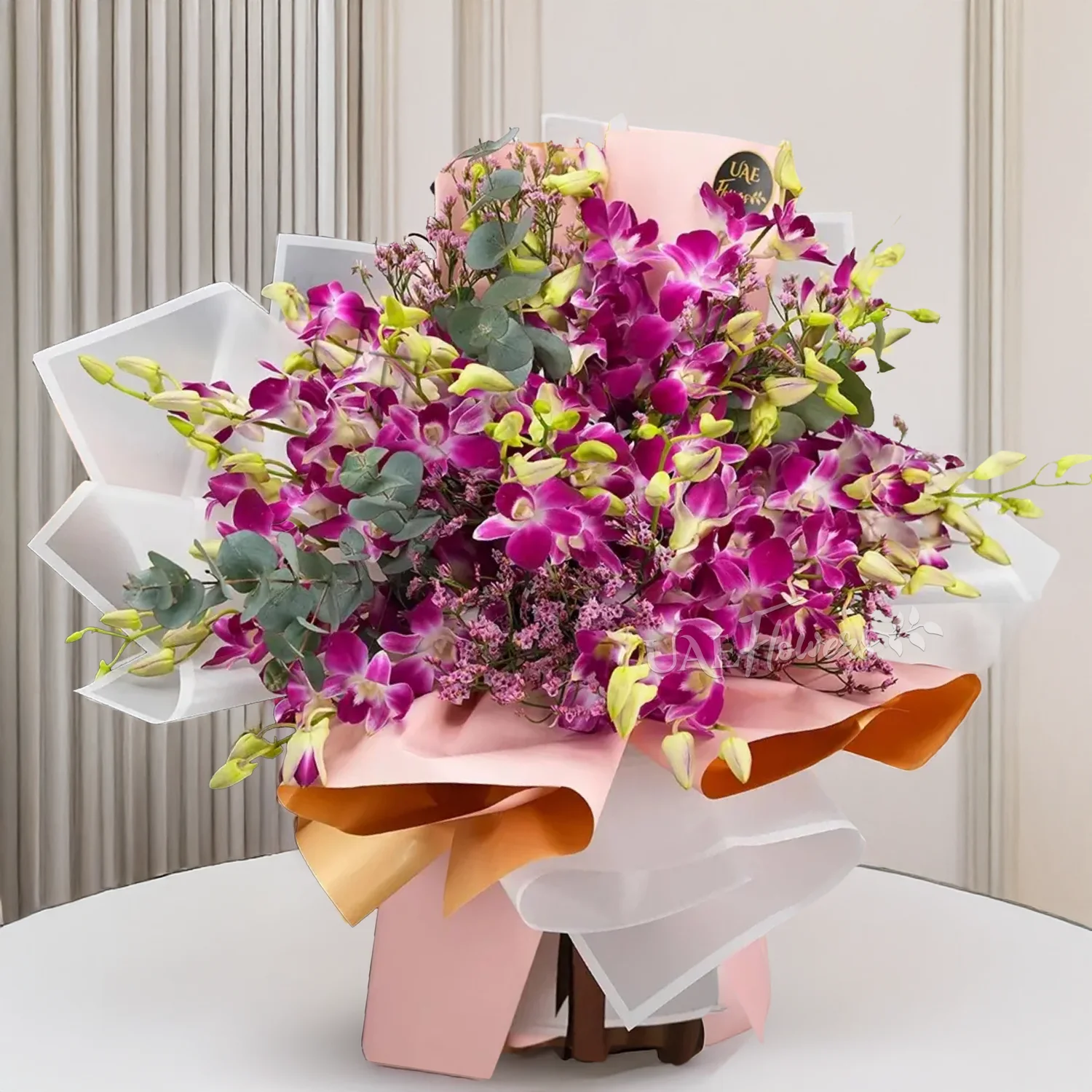 A bouquet of 20 purple orchids arranged with limonium and eucalyptus leaf fillers in pink and white wrapping tied with brown ribbon