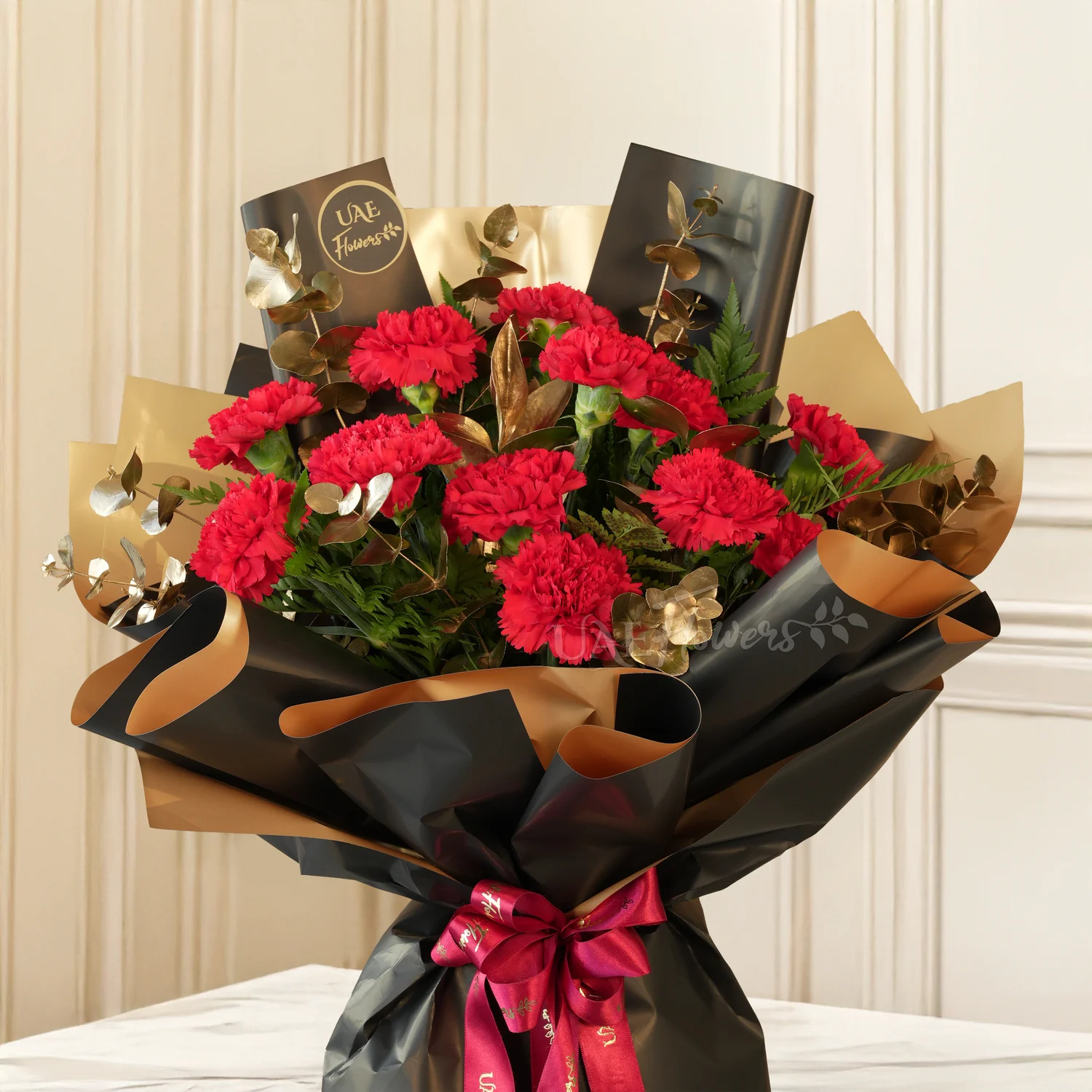 bouquet of 10 red carnations with golden eucalyptus in black and gold wrap
