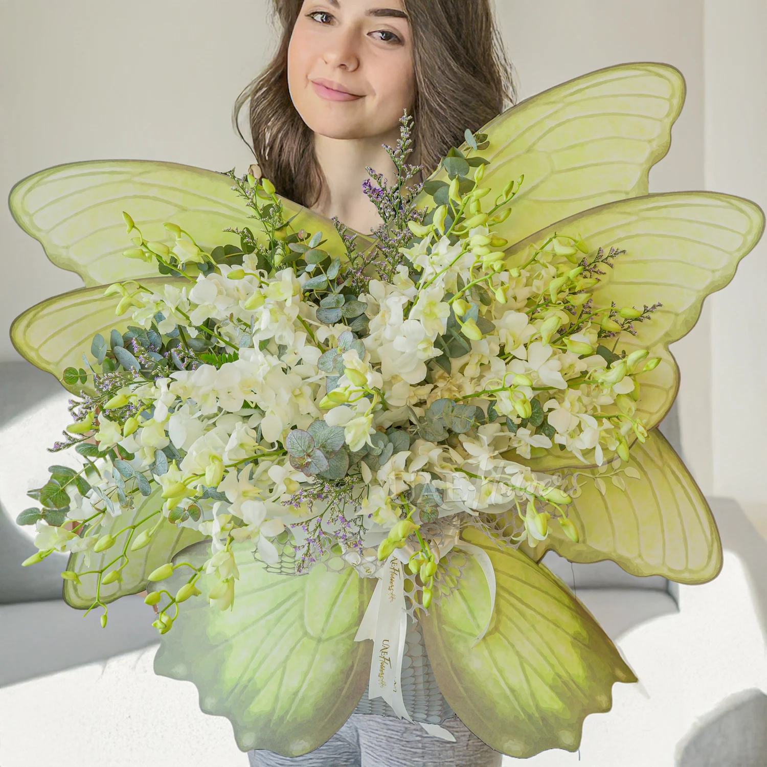 Butterfly-shaped bouquet of white orchids with green fillers and ribbon tie
