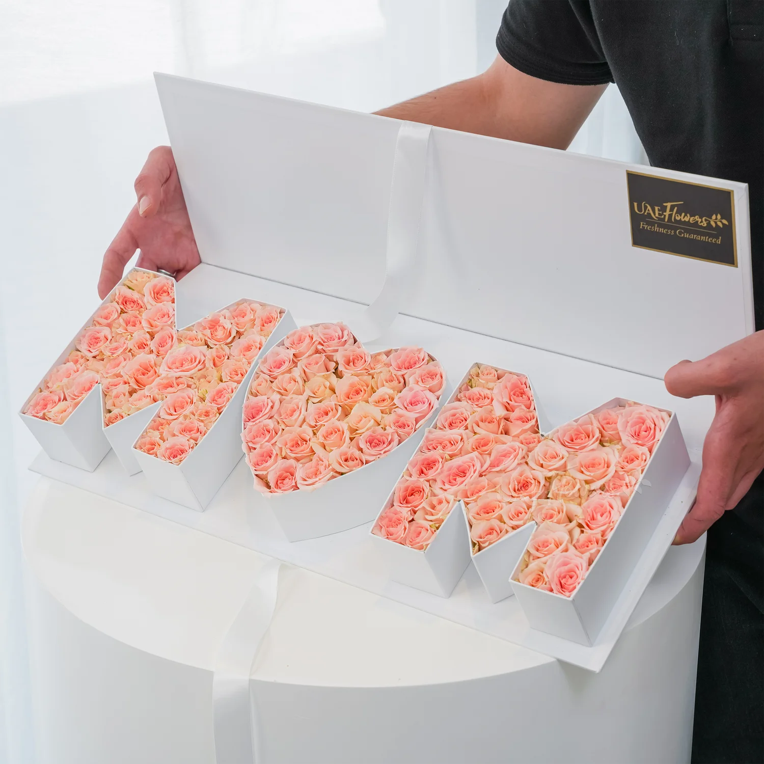 Heartfelt floral arrangement of 30 pink spray roses in a white MOM-shaped box – a perfect gift for Mother’s Day by UAE Flowers.