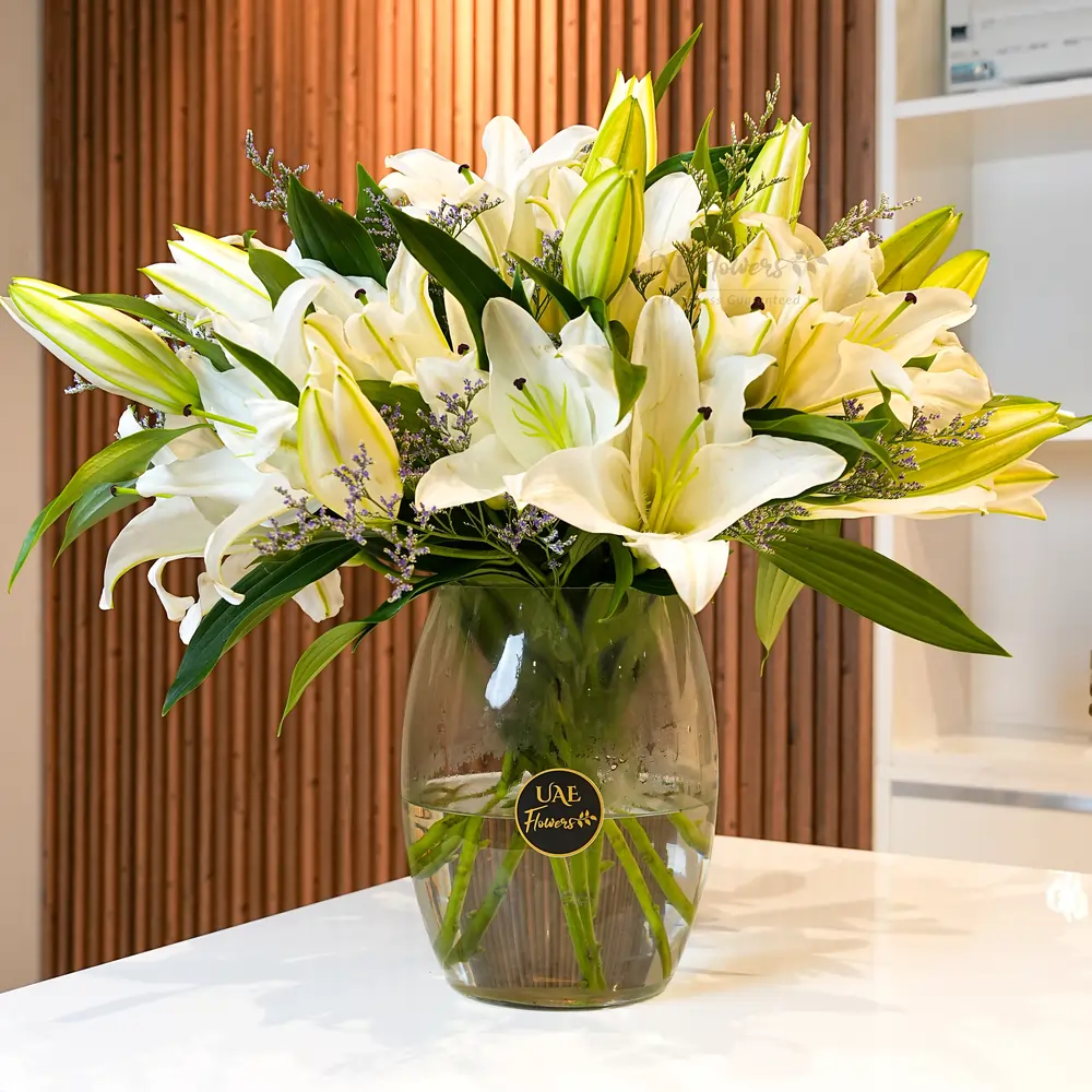 Glass vase with 10 white lilies, accented with fillers and limonium for an elegant display.