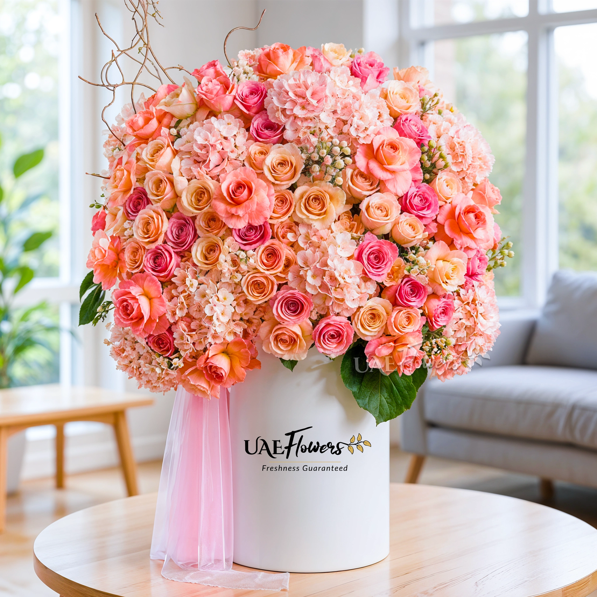 An arrangement of peach hydrangeas, peach roses and white hypericum with green fillers and pink net in a tall white box.