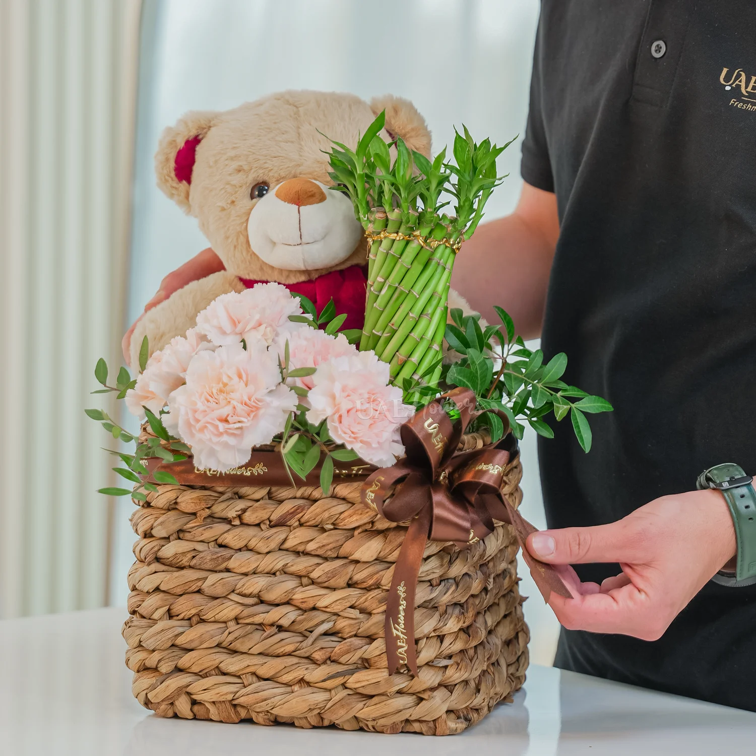 5 pink carnations, a brown teddy bear and a Lucky Wheel Bamboo plant
