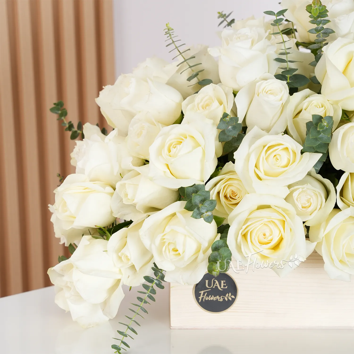 Wooden box with 40 white roses, fresh eucalyptus leaves, and green fillers for an elegant floral display.